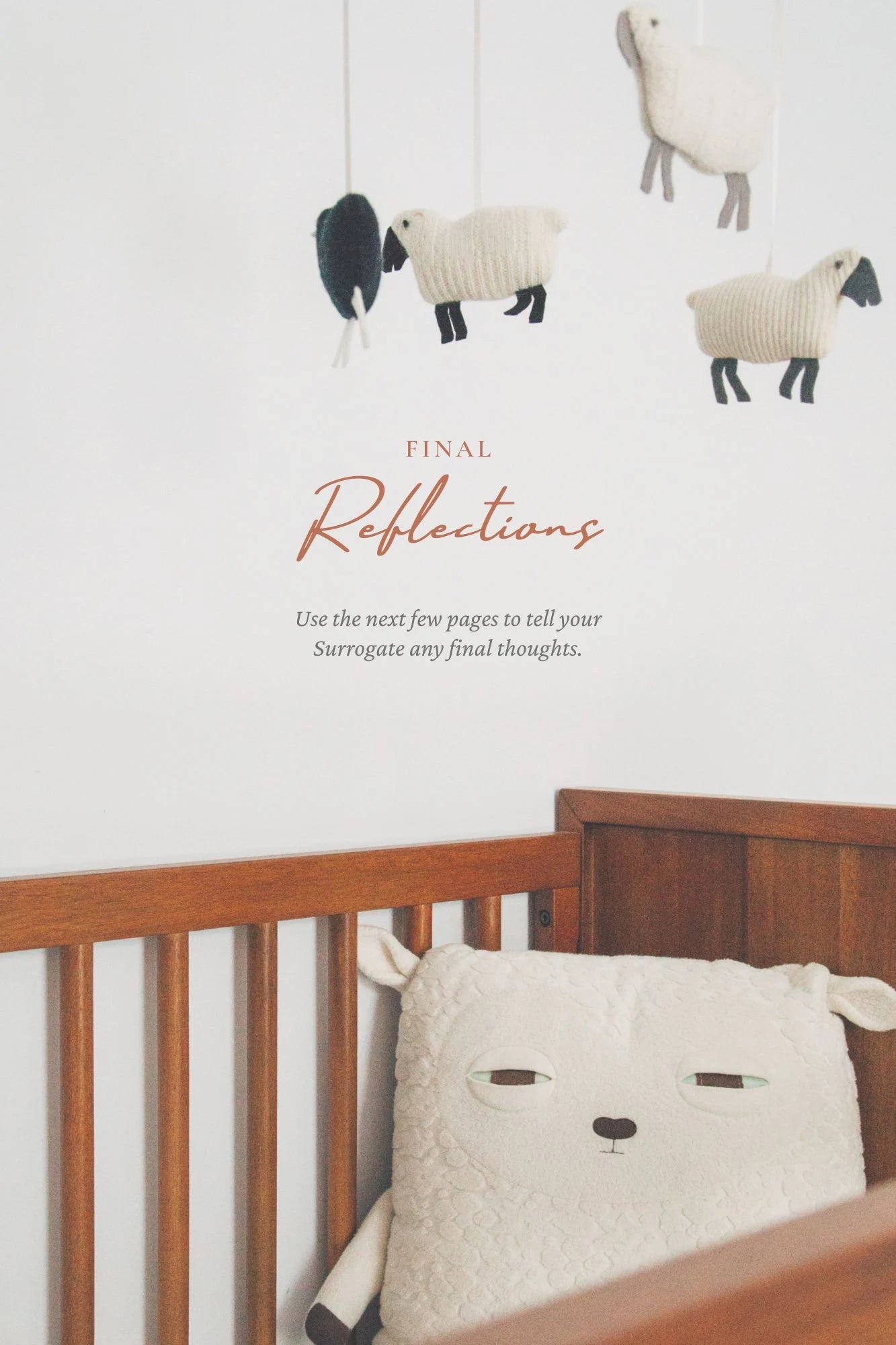 Sheep-themed crib mobile above a wooden crib with a sheep-shaped pillow on a white background.